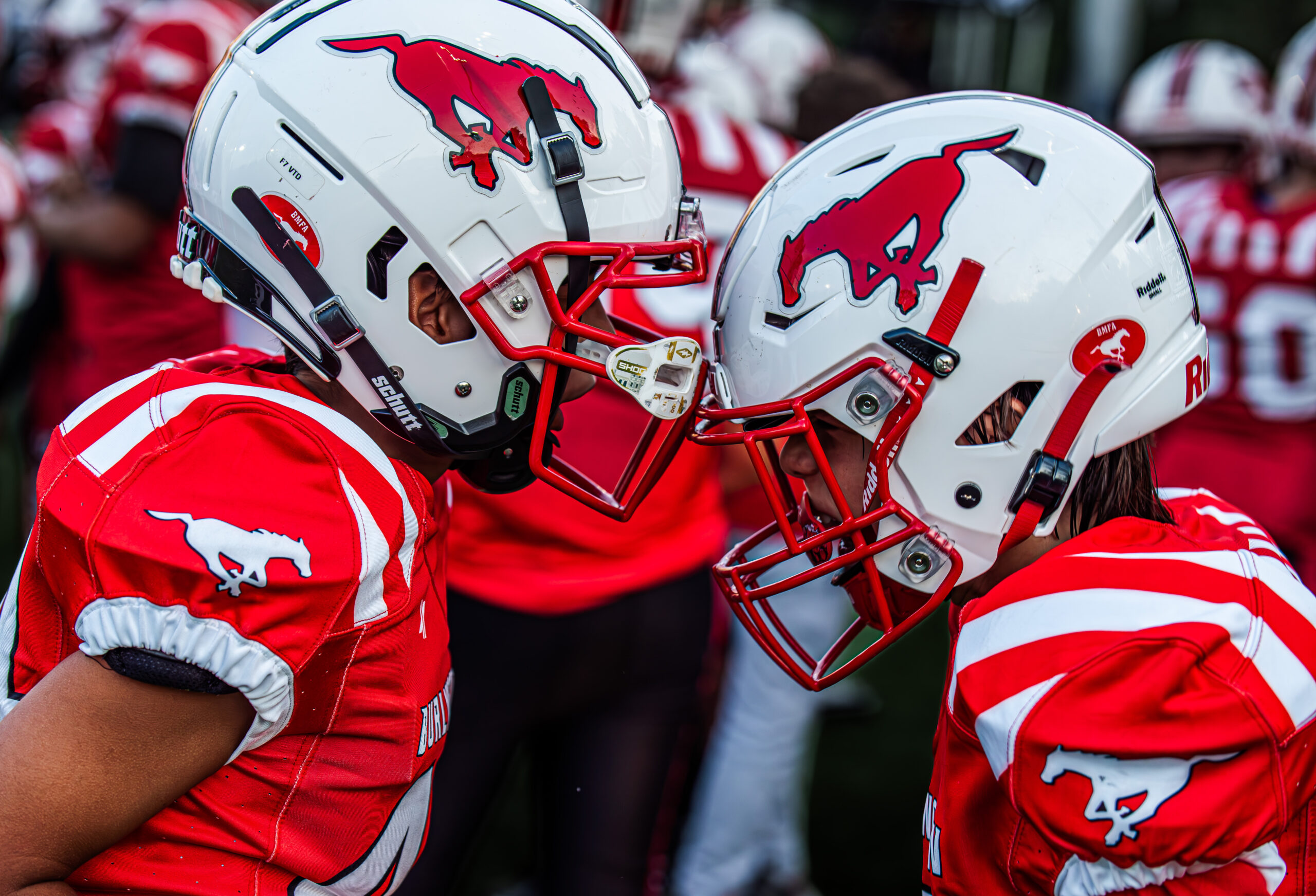 Two Burlington Stampeders players meet helmet-to-helmet before kickoff.